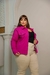 Modelo usando jaqueta plus size rosa com calça clara em ambiente neutro.