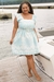 Modelo usando vestido plus size balonê em estampa azul claro, posando à beira de um lago.
