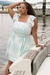 Modelo usando um vestido plus size balonê em um ambiente náutico, com detalhes em azul e branco.