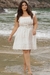Modelo usando vestido plus size balonê em um ambiente de praia, com detalhes florais e cinto na cintura.