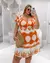 Mulher usando um vestido plus size laranja com estampa de conchas, posando em um ambiente moderno.
