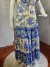Vestido plus size estampado em off white e azul, com detalhes florais, exibido em manequim.