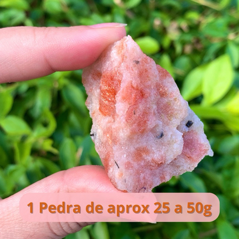 Uma pedra do sol verdadeira, com brilho natural, pesando entre 25 e 50g, sendo segurada por uma mão.