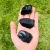 Pedra bruta de obsidiana negra natural,  exibida na palma da mão com fundo de folhas verdes