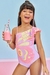 Menina sorridente usando um maiô em jacquard rosa com estampa de borboleta, segurando um copo de bebida rosa.
