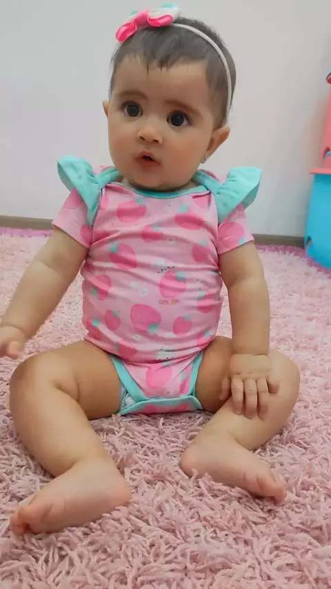 Bebê usando body infantil Kukiê em malha comfy, com estampa de frutas, sentado em um tapete rosa.