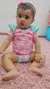 Bebê usando body infantil Kukiê em malha comfy, com estampa de frutas, sentado em um tapete rosa.