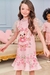 Menina usando um vestido infantil rosa com estampa de um ursinho, mangas em tule e detalhes de flores na barra.