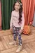 Criança sorrindo vestindo um conjunto de blusão rosa em tricot com estampa de animal e legging floral.