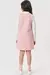 Vestido em jacquard rosa visto de trás, combinado com uma blusa branca e tênis.