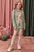 Menina vestindo blusão alongado em moletom verde com estampa de menina e gato, e calça legging floral branca
