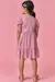 Vestido infantil rosa com estampa de corações, visto de costas, com detalhe de babado na saia.