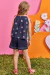Conjunto infantil kukiê com blusa boxy e shorts em malha fresh, estampado com flores e abelhas, visto de costas por uma menina.