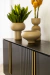 Buffet Aline 4 portas com design assinado, decorado com vasos e plantas em uma mesa escura.