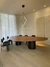 Mesa de jantar orgânica Liv com design oval, rodeada por cadeiras pretas em ambiente iluminado e moderno.