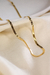 Choker Malha Fita Lavinia banhado a ouro 18k sobre tecido claro.