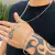 Corrente de prata 2mm com um pingente, usada por uma pessoa com uma tatuagem no braço e uma pulseira de prata.