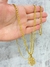 Corrente banhada a ouro 18k com pulseira e pingente em forma de cifrão, exibida na palma da mão.