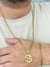 Corrente banhada a ouro 18k com pingente de cifrão, acompanhada de pulseira, em uma mão masculina.