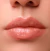 Boca feminina com gloss labial cor de rosa claro e brilho intenso