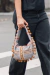 Bolsa Bunny Dots Colorida G com detalhes em pompons, sendo segurada por uma mulher vestindo uma blusa preta e calças jeans.