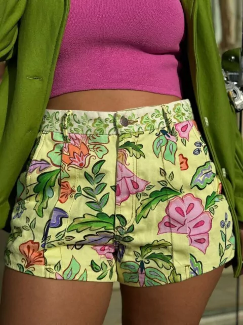 Shorts de sarja com estampa floral em tons vibrantes, combinando com top rosa e blazer verde.
