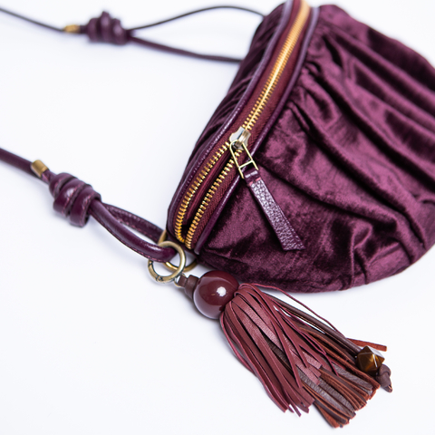 Bolsa bolchete franzida na cor vinho com zíper dourado, decorado por bag charm tipo tassel destacavel feito de couro e resina