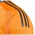 A imagem mostra uma camisa de futebol do Real Madrid, modelo Away 24/25, na cor laranja vibrante. A camisa possui um padrão geométrico dinâmico com linhas em tons de laranja mais escuros. O logo da Adidas está no lado direito do peito, enquanto o escudo d