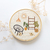 Quadro bastidor bordado a mão de um cenário com itens de decoração boho e plantas