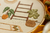 Quadro bastidor bordado a mão de um cenário com itens de decoração boho e plantas
