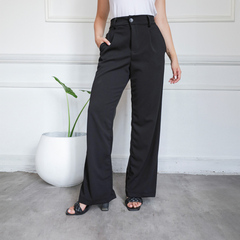 Pantalón sastrero negro de corte elegante, con bolsillos y botón en la cintura, combinado con una blusa blanca y sandalias negras.