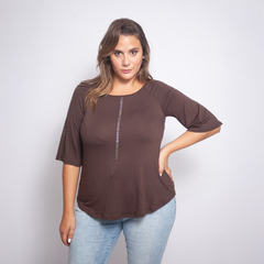 Remera marrón de manga corta para mujer, estilo casual, con detalles de costuras blancas en el centro y en las mangas, combinada con jeans claros, en un fondo gris claro.