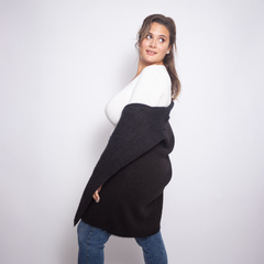 Mujer posando con un saco largo de color negro sobre una blusa blanca y jeans, mostrando una expresión amigable.