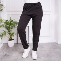 Pantalones babucha Angela en color negro, con ajuste elástico y cordón, combinados con zapatillas blancas.
