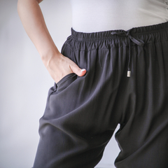 Pantalones babucha Guada en color negro, con un diseño cómodo y práctico, mostrando un bolsillo y una cintura elástica.