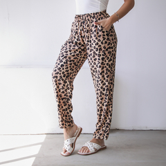 Pantalones tipo babucha con estampado de leopardo, con cintura elástica y bolsillos, combinados con sandalias blancas.