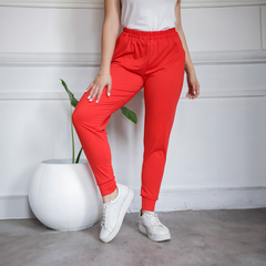 Pantalones babucha Milia en color rojo, con cintura elástica y puños, combinados con zapatillas blancas.