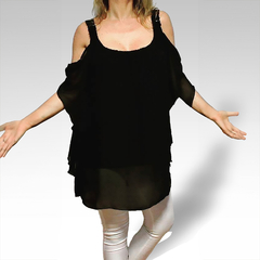 Blusa negra de estilo holgado, con tirantes en los hombros, presentada por una modelo con pantalones plateados.