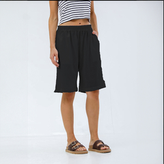 Bermuda negra con cintura elástica, mostrada en una modelo con una camiseta de rayas.