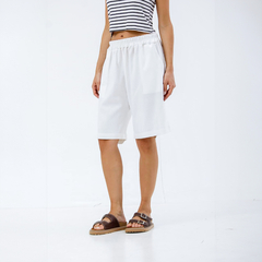 Bermuda blanca de mujer con cintura elástica, combinada con una camiseta de rayas y sandalias.
