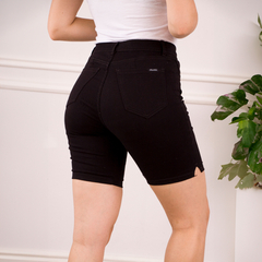 Bermudas negras ajustadas vistas desde atrás, con detalle de corte en la parte inferior, usadas por una mujer.