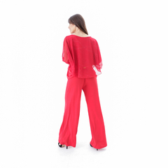 Pantalones palazzo rojos, con una mujer de espaldas que lleva una blusa transparente a juego.