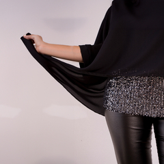 Blusa elegante de color negro con detalles brillantes en la parte inferior, usada con pantalones ajustados.
