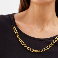 Detalle de la blusa Carmen con un collar dorado sobre fondo negro.