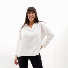 Modelo sonriente usando una blusa blanca de manga larga con cuello en V.