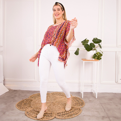 Modelo usando una blusa colorida con estampado zigzagueante, combinada con pantalones blancos y zapatos claros.