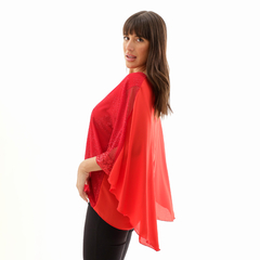 Blusa Erea de color rojo con mangas amplias y detalles brillantes, modelo posando de perfil.