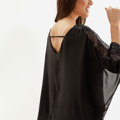 Vista trasera de una blusa negra con detalles brillantes en las mangas