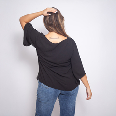 Blusa negra Felisa vista desde atrás, con mangas anchas, combinada con jeans azules.