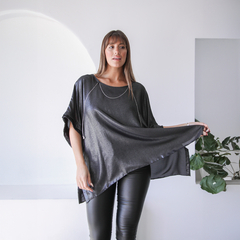 Blusa Ginebra elegante de color negro, con un diseño amplio y detalles brillantes, combinada con pantalones ajustados.